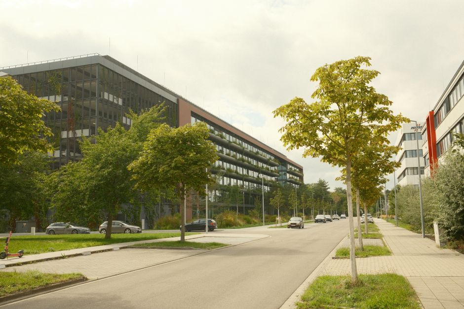 Infraestrutura Verde — A modern urban street with office buildings and greenery on a cloudy day.